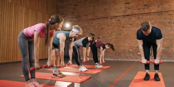 Fitness group performing exercises with dumbbells in a modern yoga studio setting.