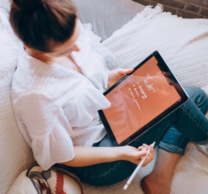 A woman relaxes on a sofa with a digital tablet, enjoying leisure time in a cozy home environment.