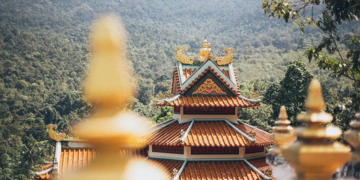 Beautiful temple architecture nestled in a lush, mountainous setting on a sunny day.
