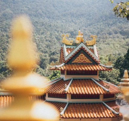 Beautiful temple architecture nestled in a lush, mountainous setting on a sunny day.