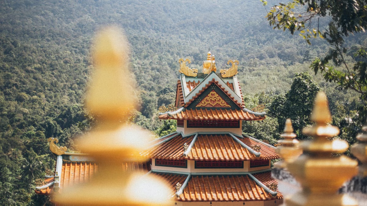 Beautiful temple architecture nestled in a lush, mountainous setting on a sunny day.
